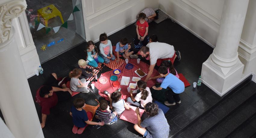Niños y niñas en ronda sentados merendando, vistos desde arriba.